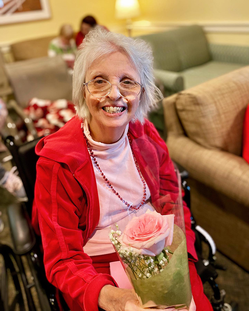 A resident in a red outfit holding a flower bouquet