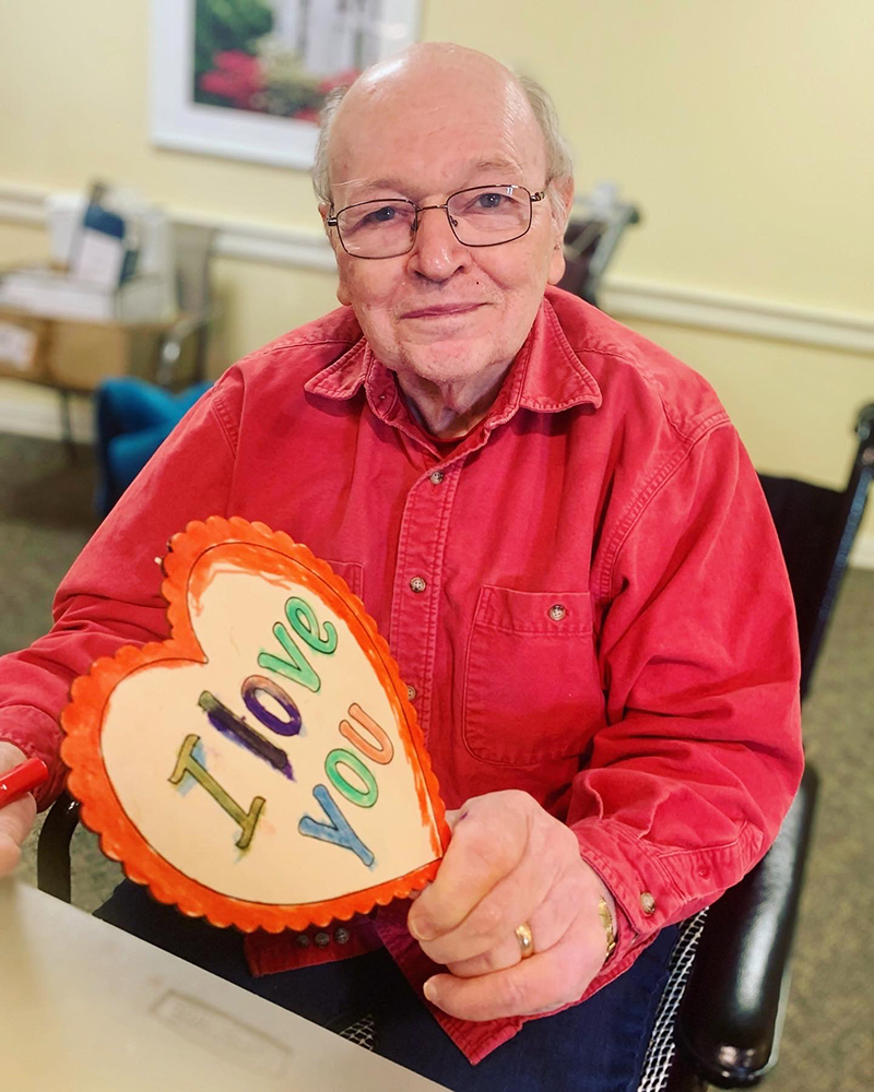 A resident holding a handmade heart that says 'I love you'