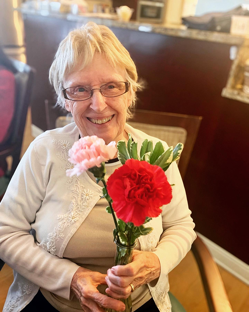 Resident holding flowers with a smile