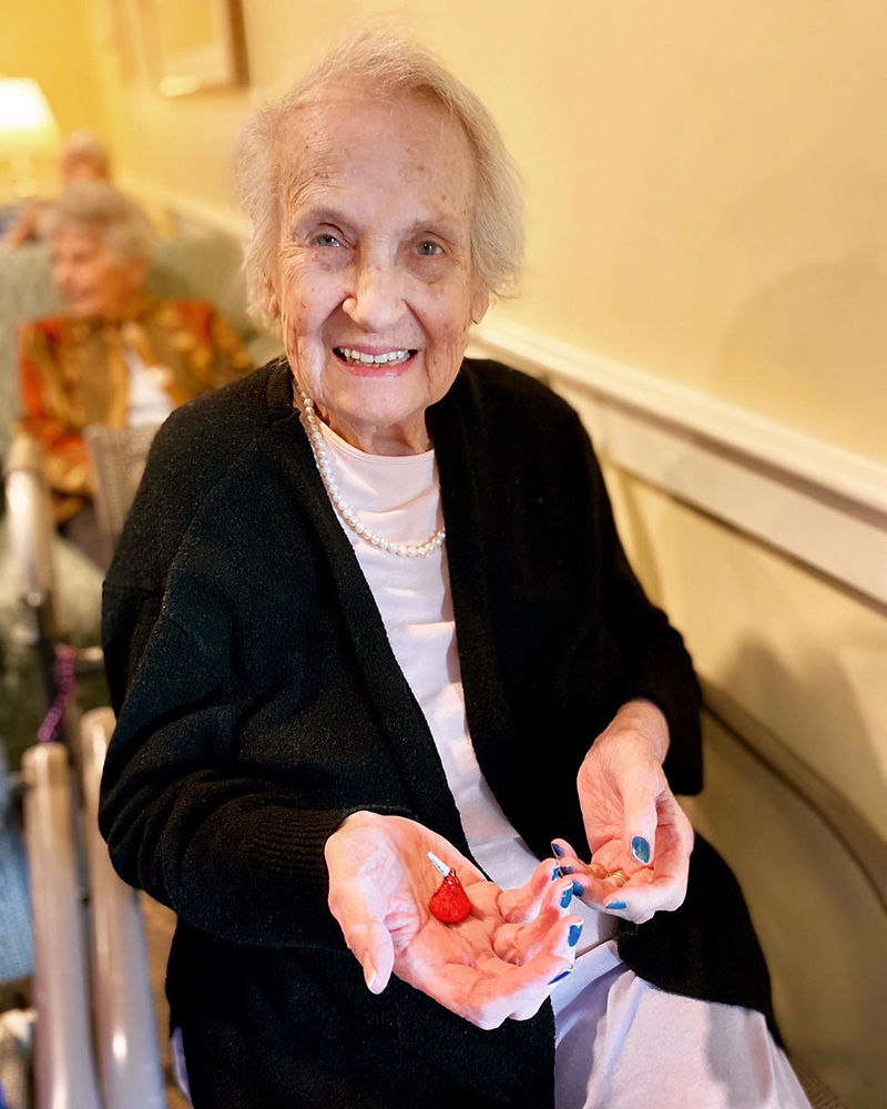 Resident smiling while showing colorful items in her hands