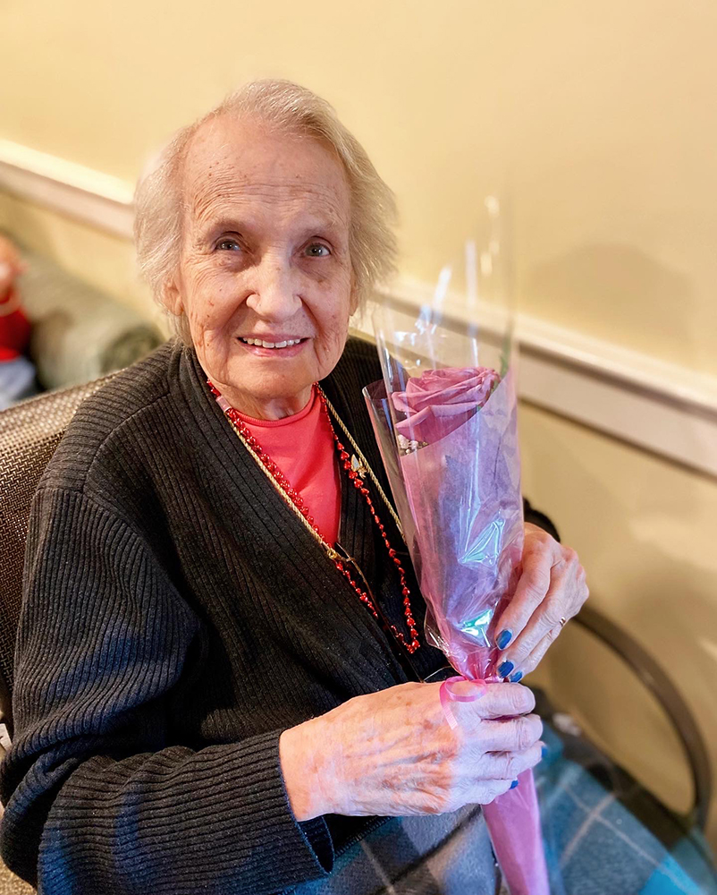 Resident holding a flower bouquet in a cozy setting