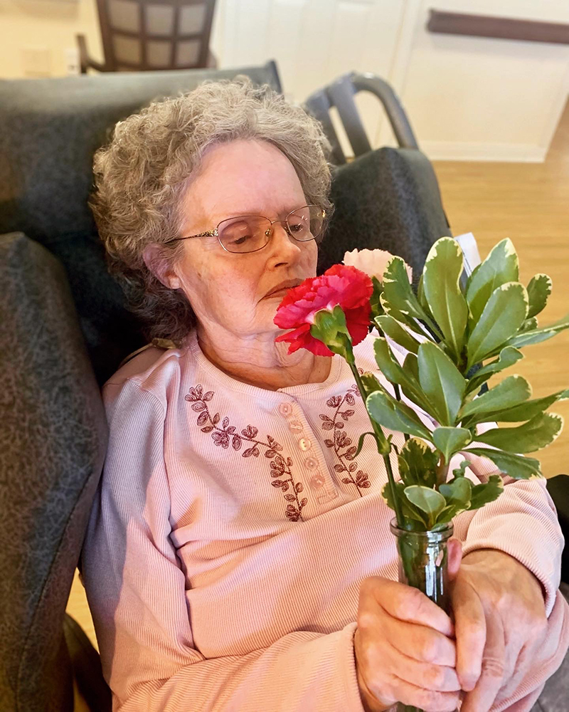 A resident enjoying flowers in a cozy chair