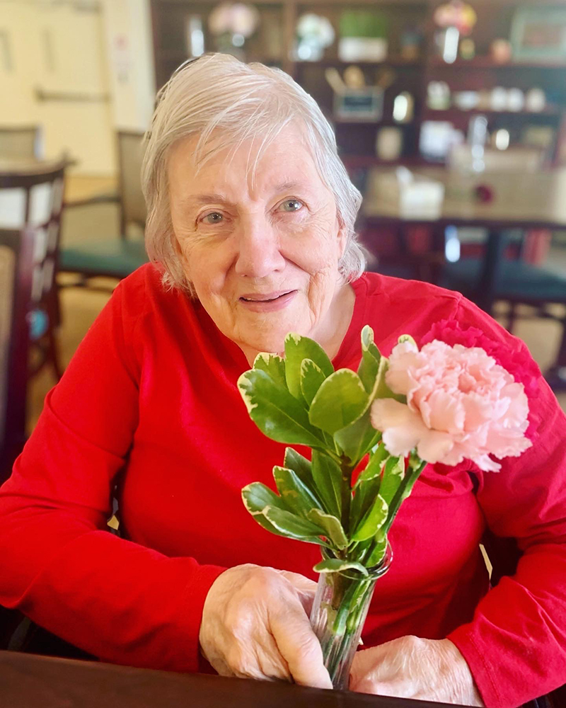 Resident holding a small bouquet of flowers in a common area