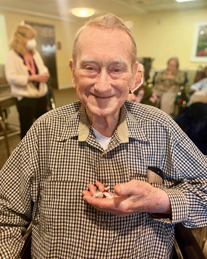 A resident smiling while holding candy in an activity room