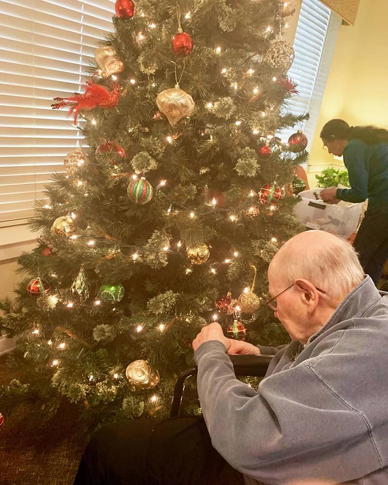 Resident decorating a Christmas tree with staff member
