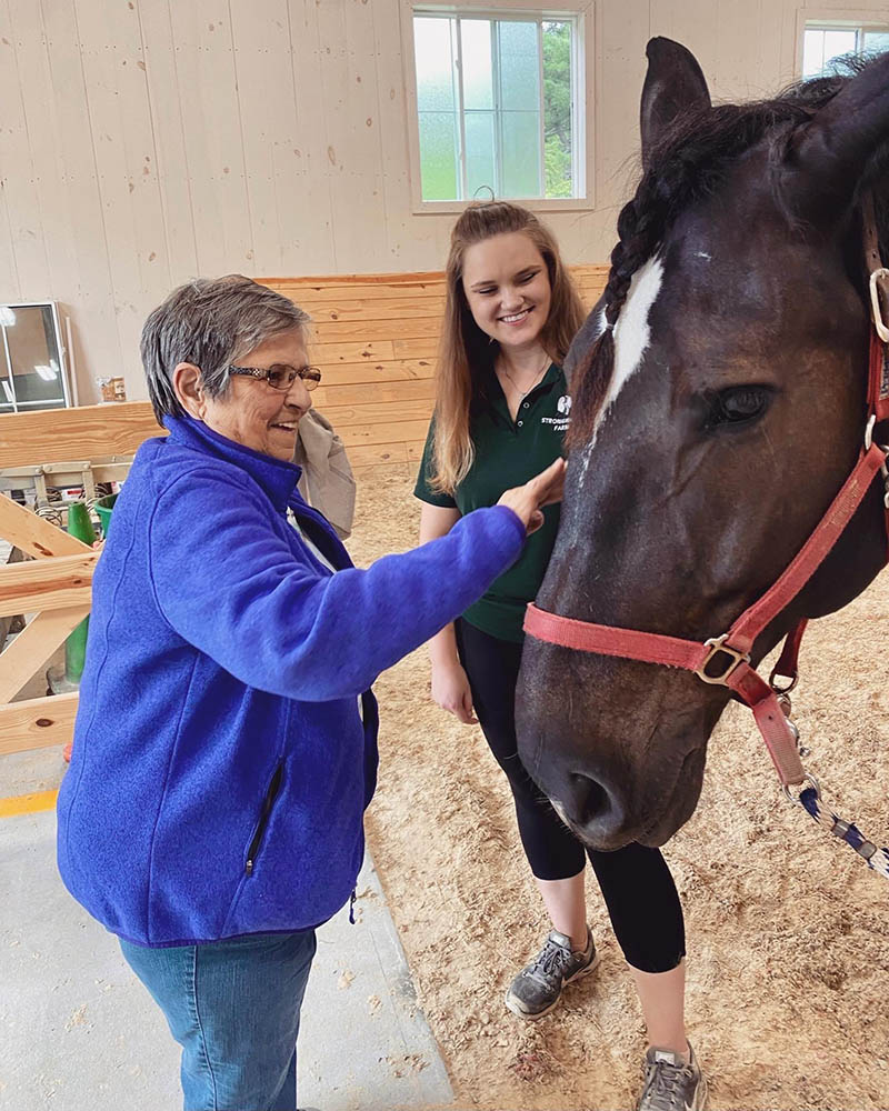 Resident interacting with a horse in an indoor setting