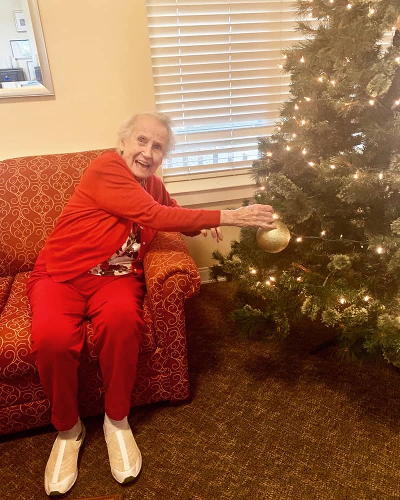 Resident decorating a Christmas tree in a cozy living room