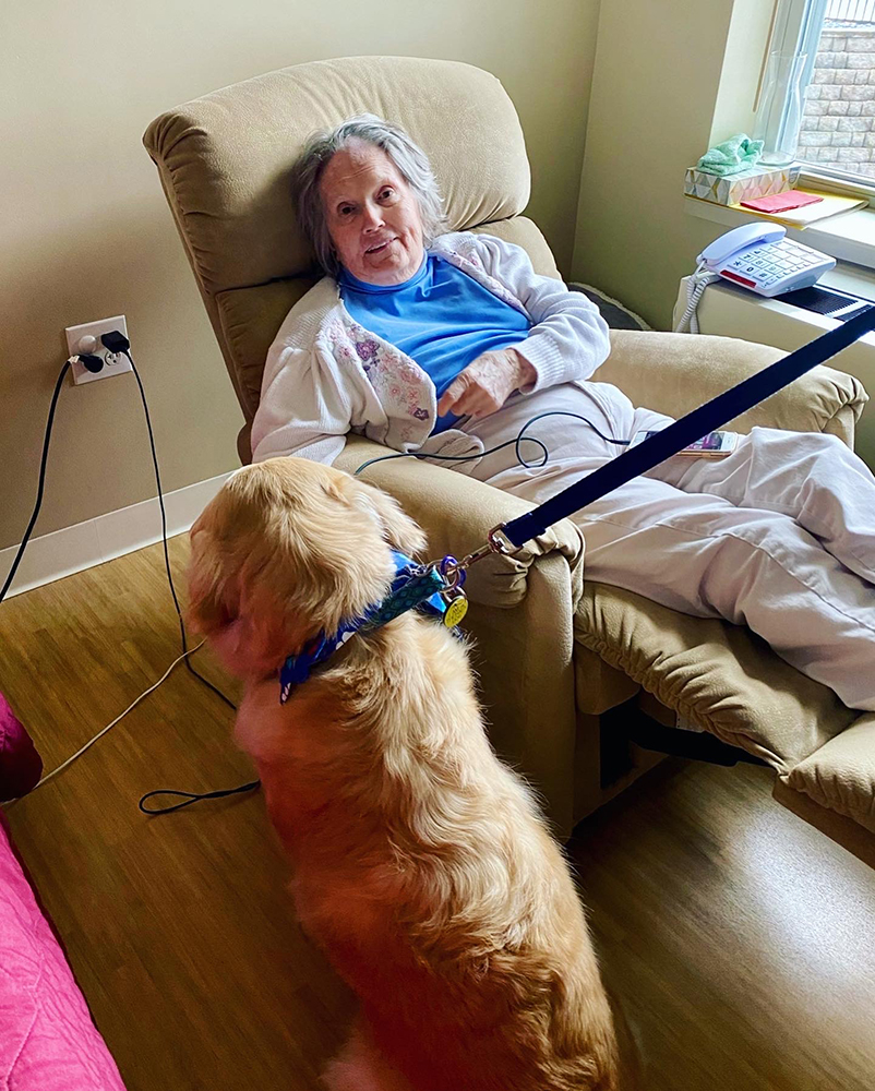 Resident interacting with a dog in a cozy chair