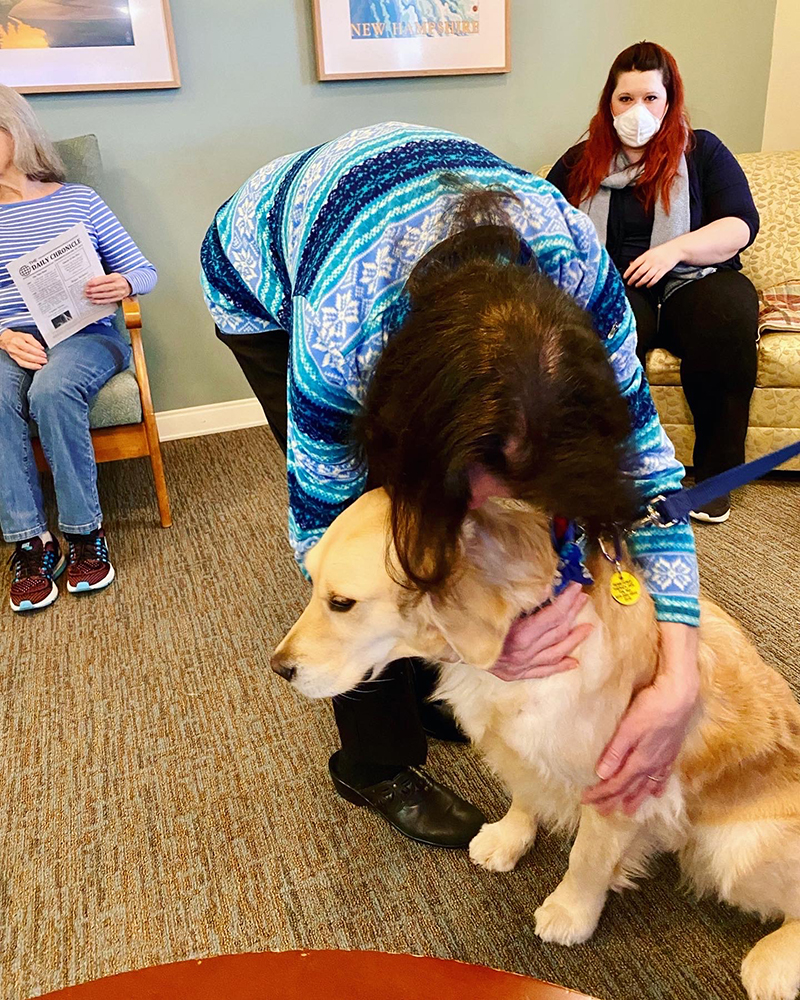 Resident interacting with a therapy dog in a common area