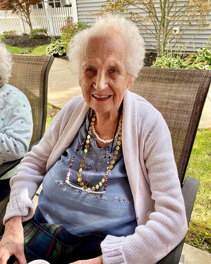 Smiling resident outdoors with necklaces in a garden
