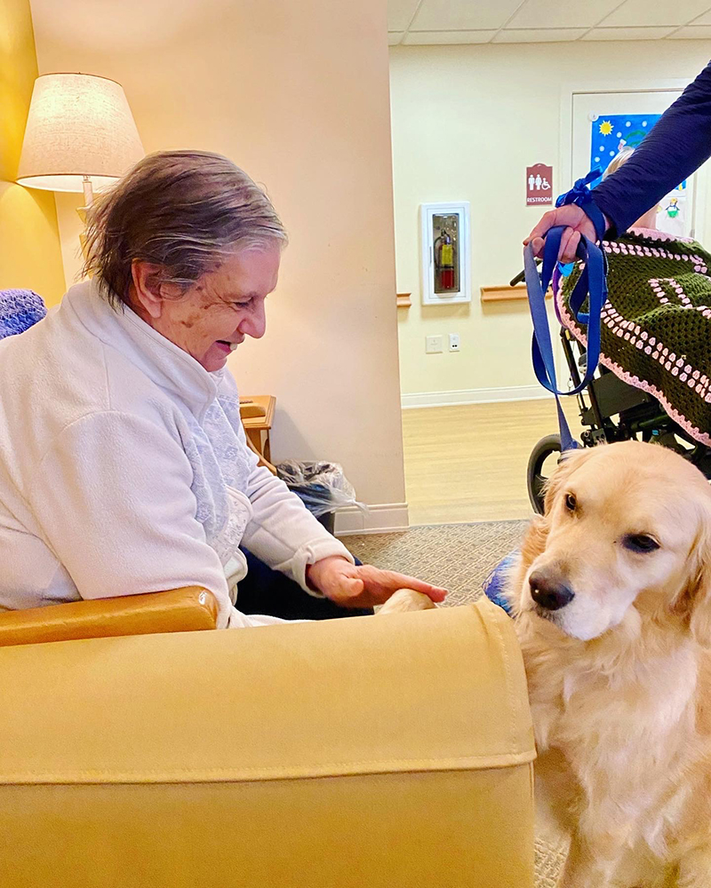 Resident interacting with a dog in a cozy common area