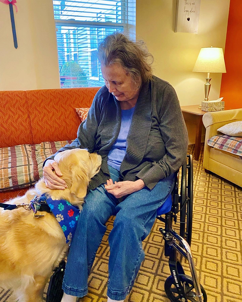 A resident sharing a moment with a therapy dog