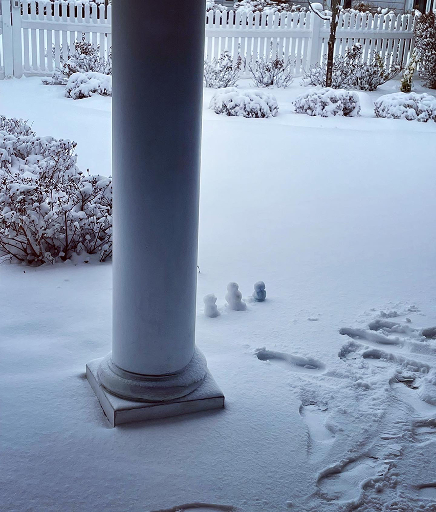 Snow-covered landscape with small snowmen near a pillar