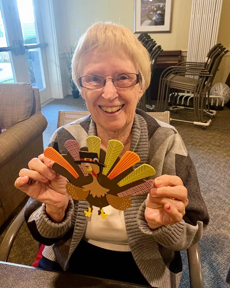 Resident holding a turkey decoration with a smile