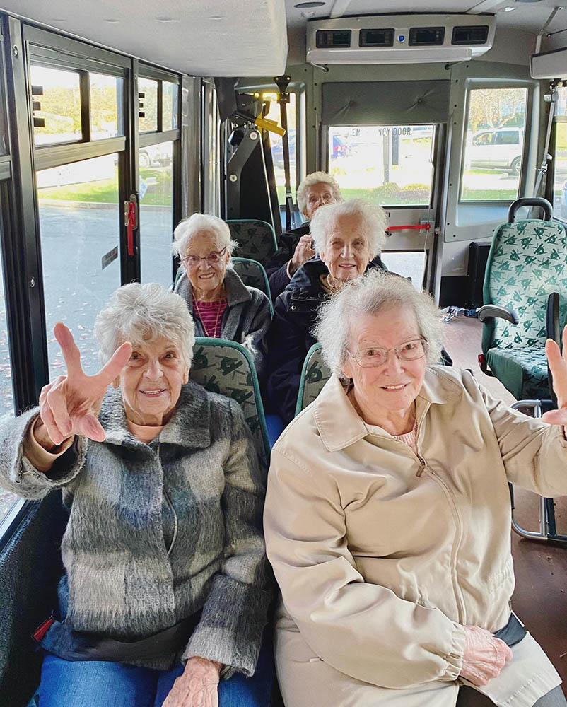 Residents smiling and showing peace signs on a shuttle bus