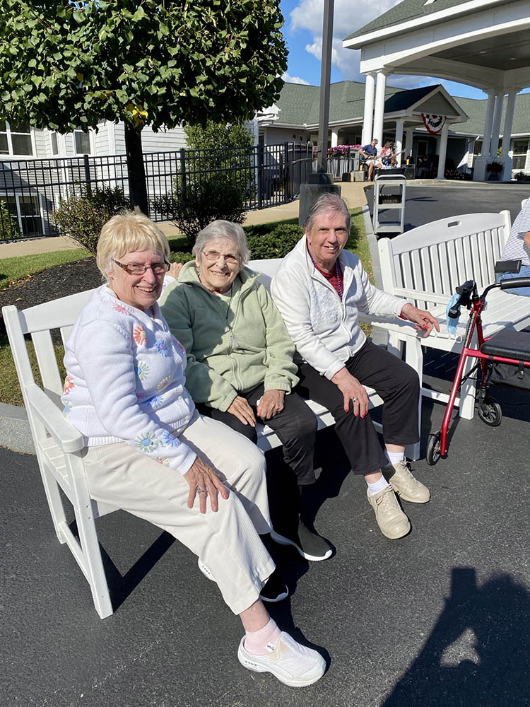 Three residents sitting outdoors at the facility