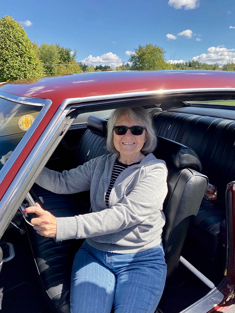 A smiling resident driving a classic car outdoors