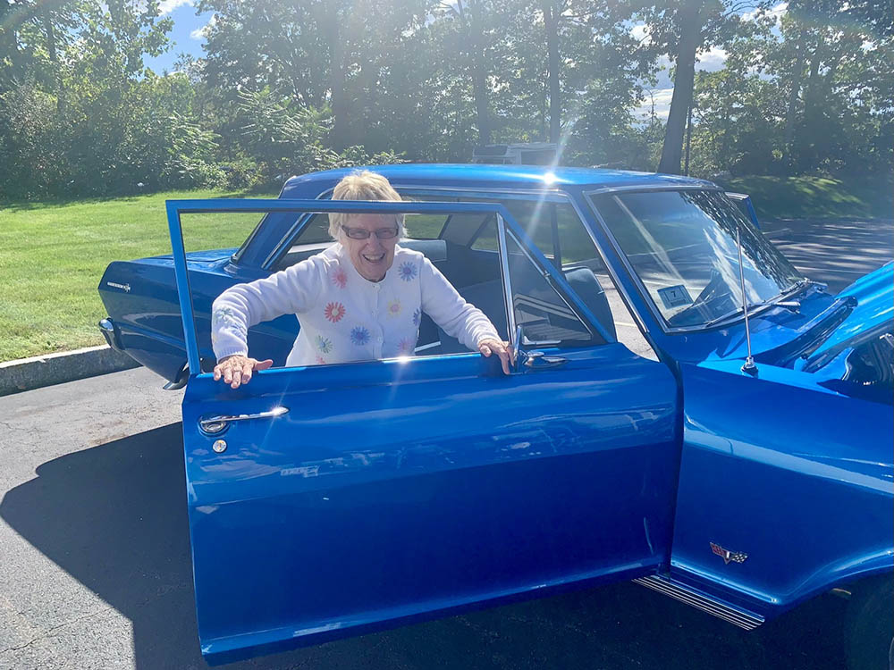 Resident getting into a blue car in a sunny outdoor setting