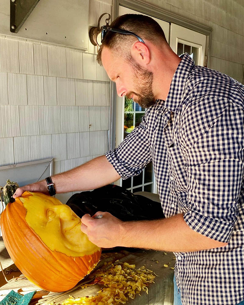 Man carving a pumpkin outdoors