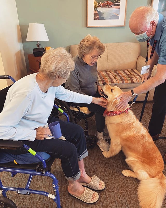 Residents interacting with a therapy dog in a common area