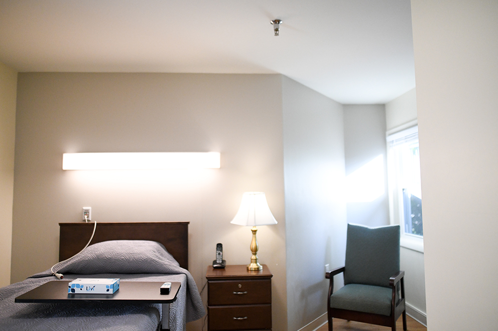 A cozy resident room with a bed and chair