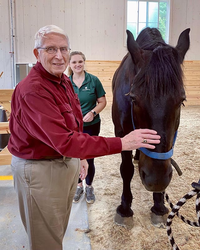 Resident interacting with a horse with staff member present