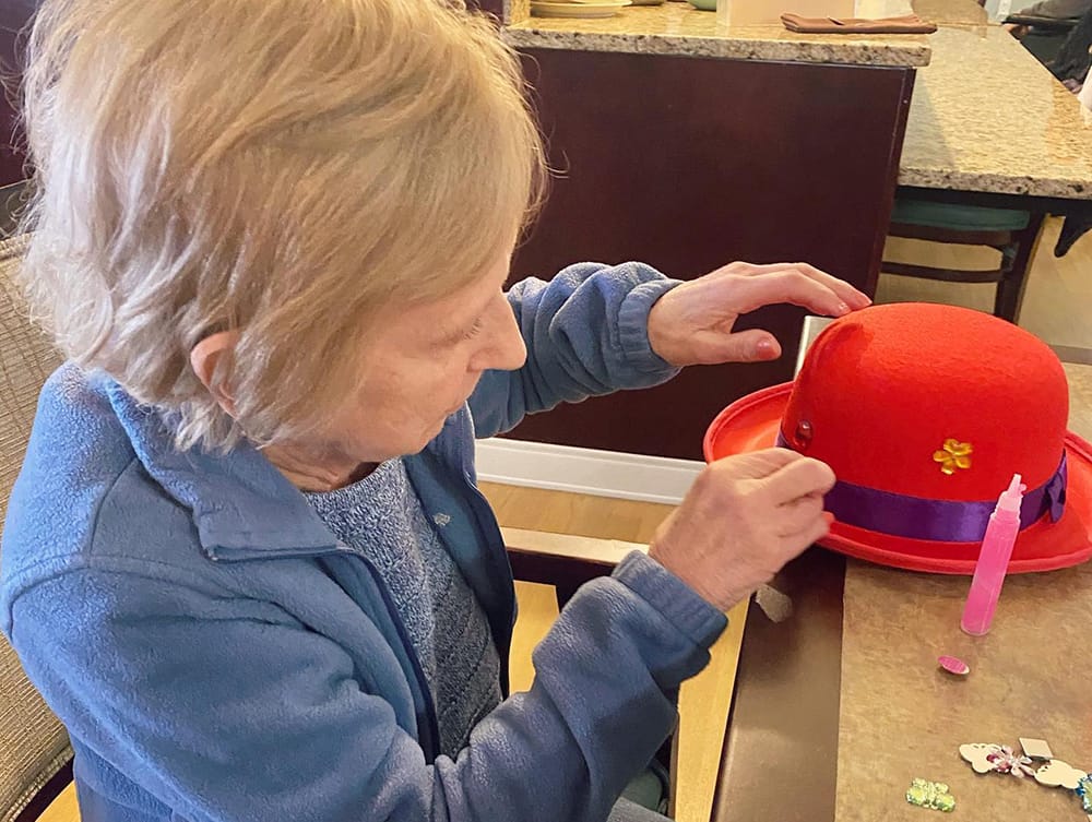 A resident crafting at a table in a common area