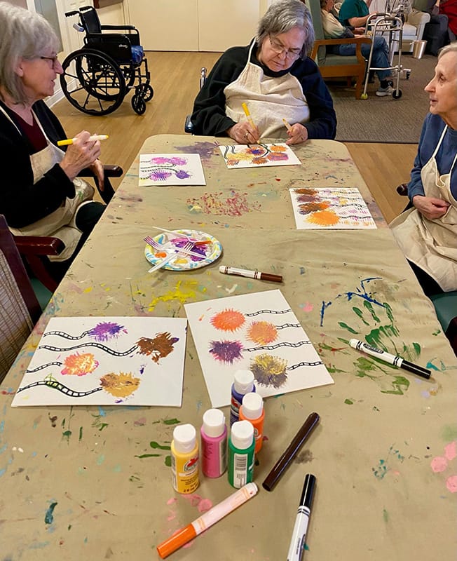Residents engaged in a painting activity at a communal table