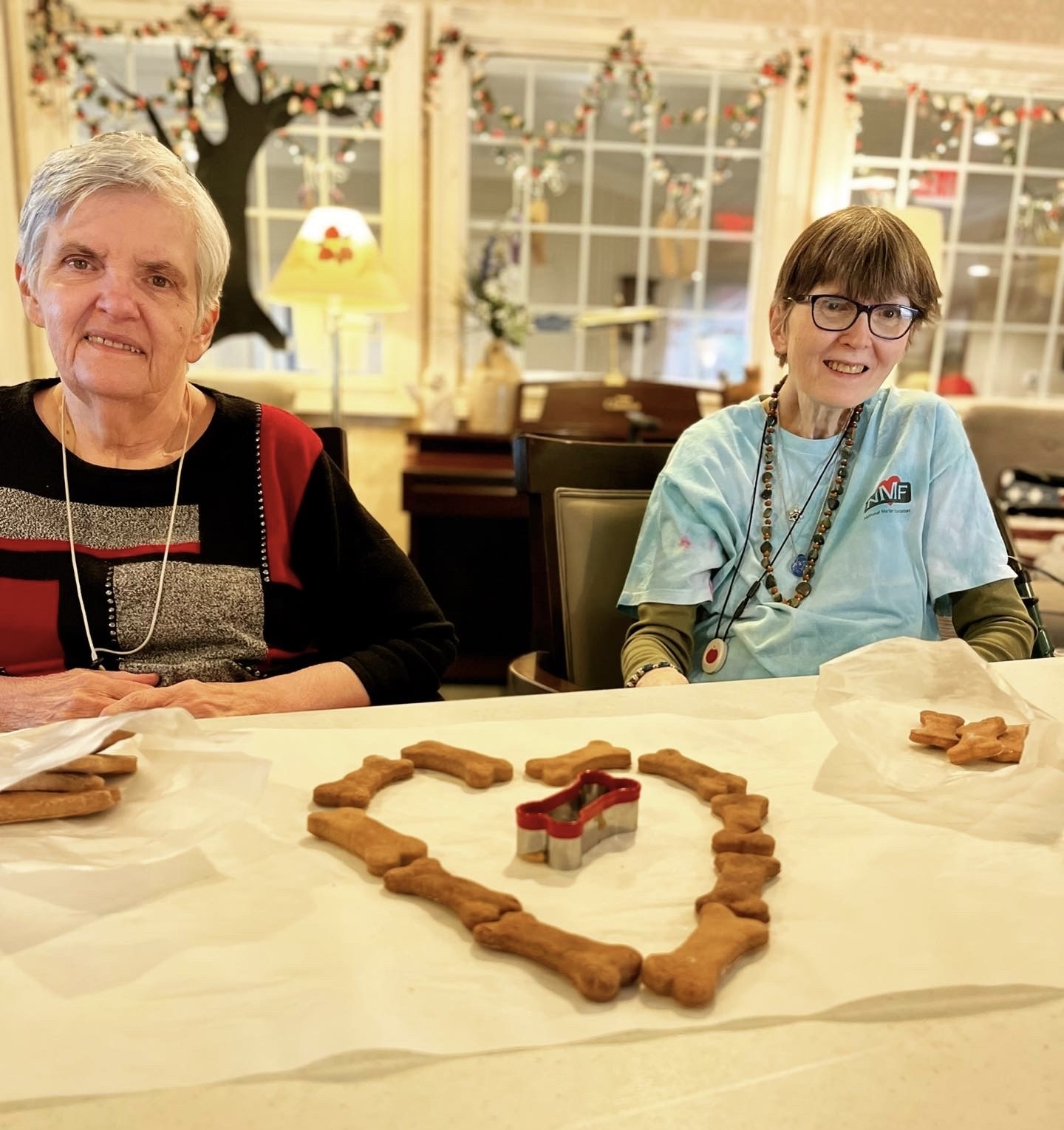 Two residents making heart-shaped cookies in a common area
