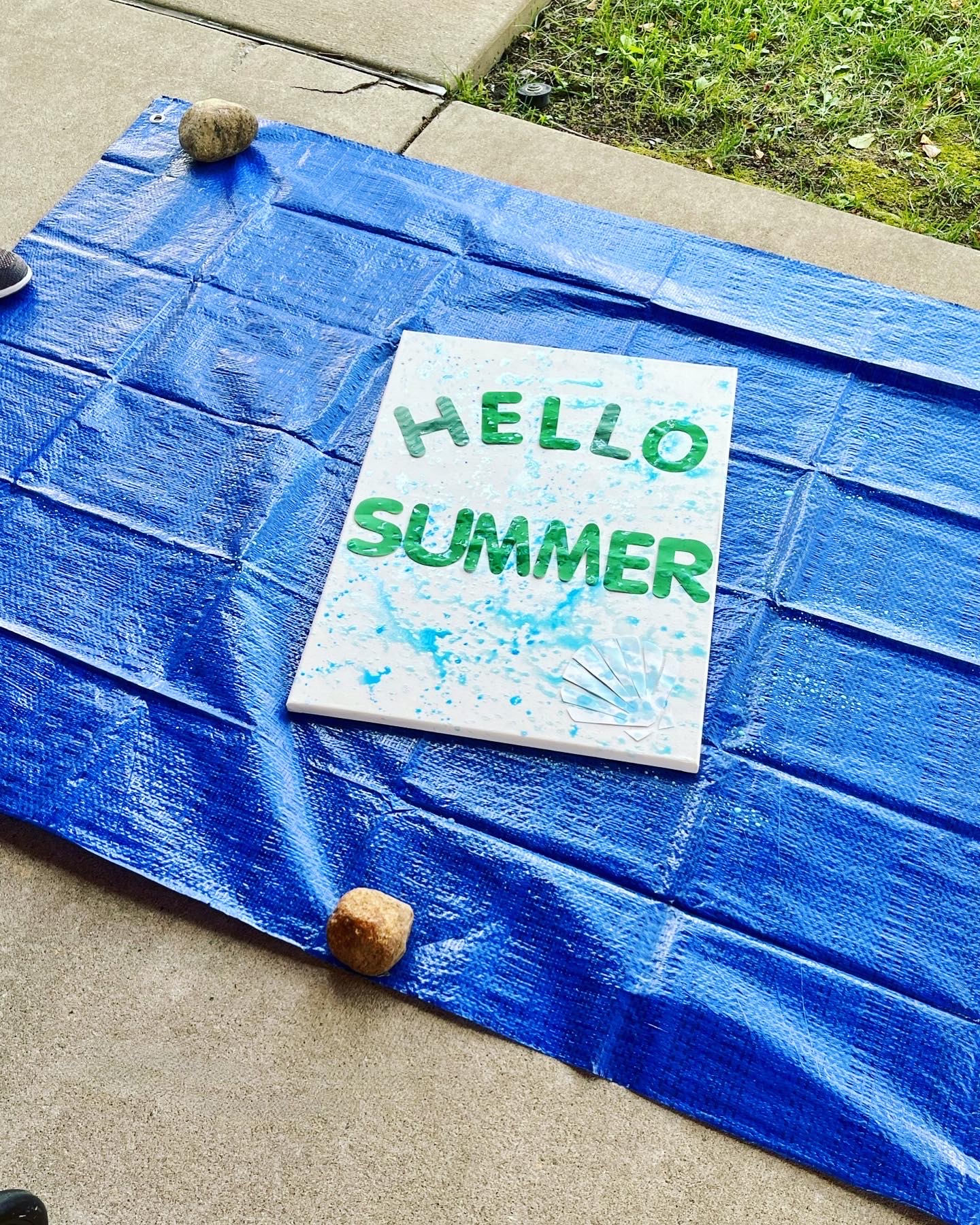 Painting on a blue tarp with the words 'HELLO SUMMER'
