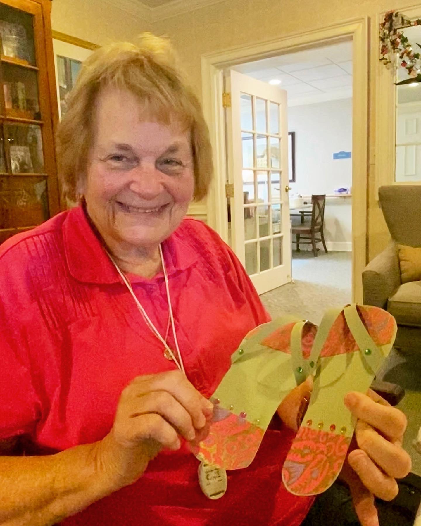 Resident showing a colorful craft project with a smile