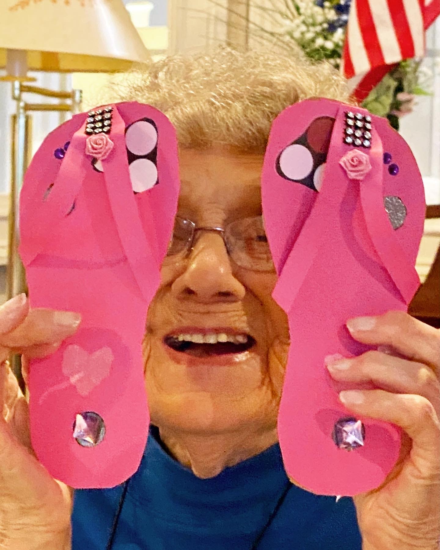 Resident holding up pink flip-flops made from craft materials