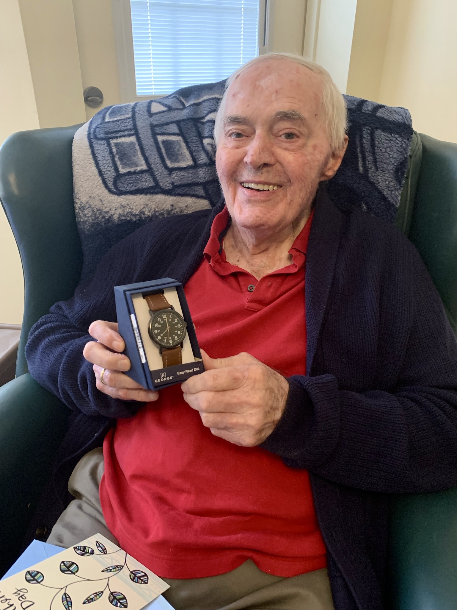 A resident holding a watch gift in a cozy chair