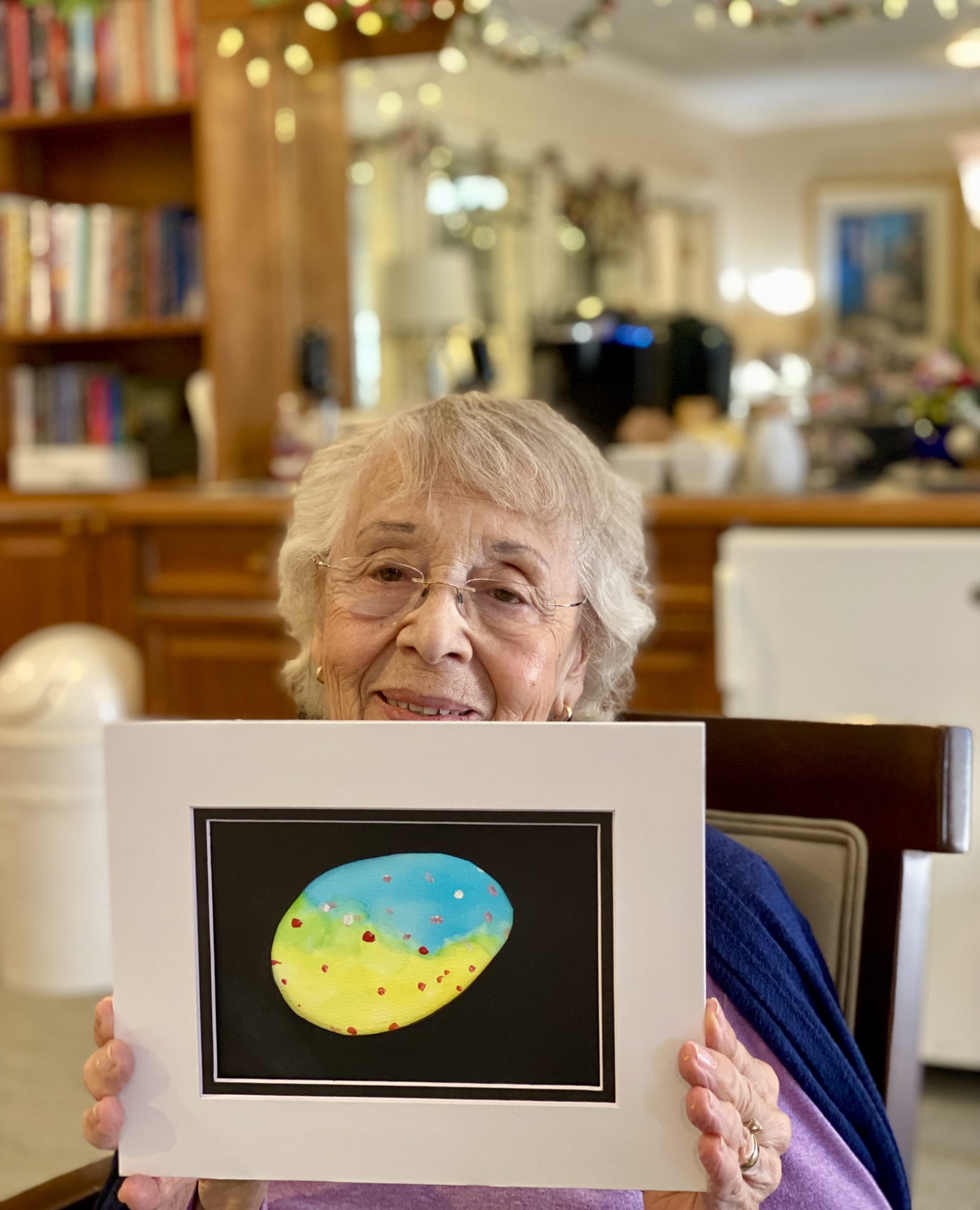 Resident holding a colorful art piece in a common area