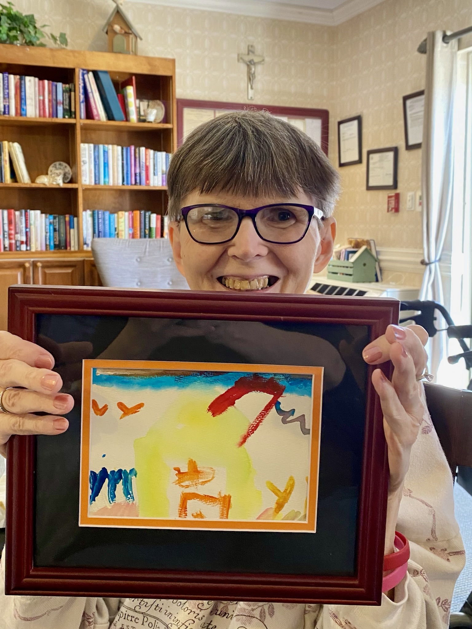 Resident holding up a colorful painting in a common area