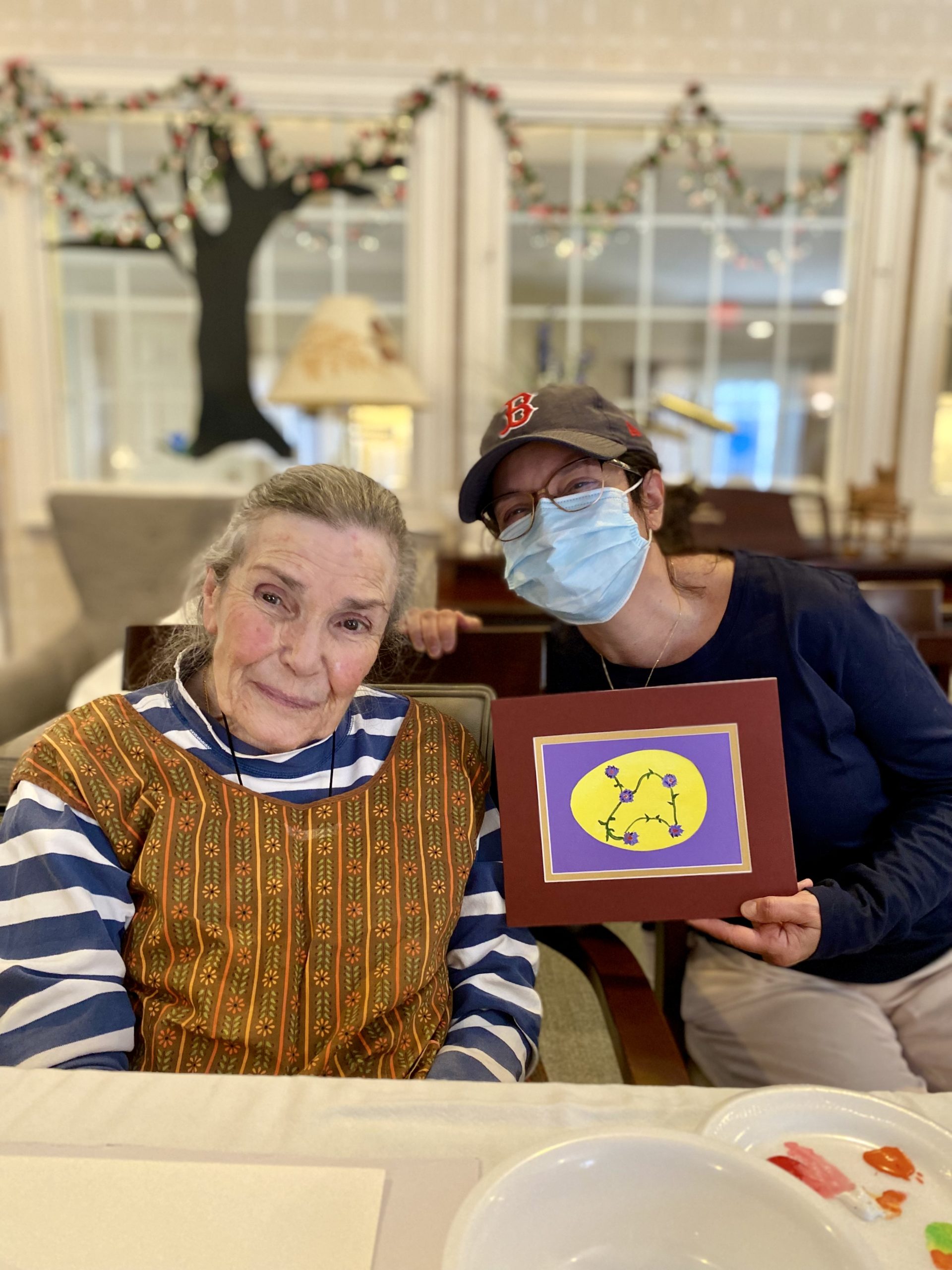 A resident and staff member showing artwork in a common area