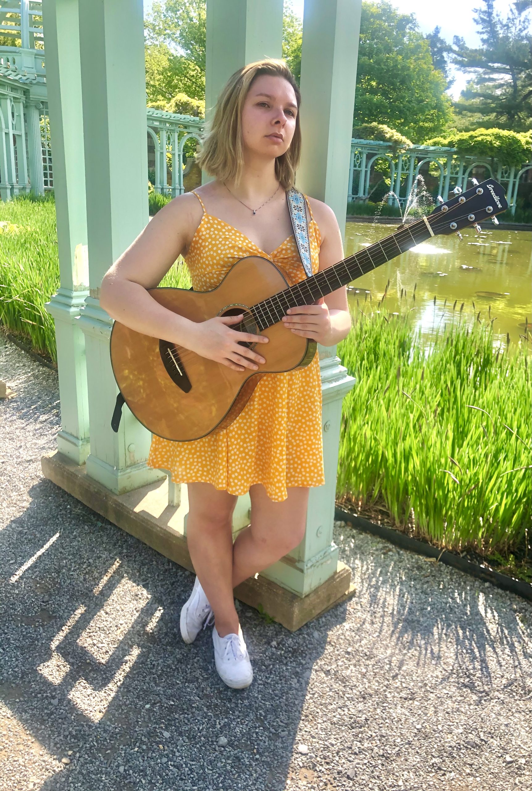 A young woman playing guitar in a garden