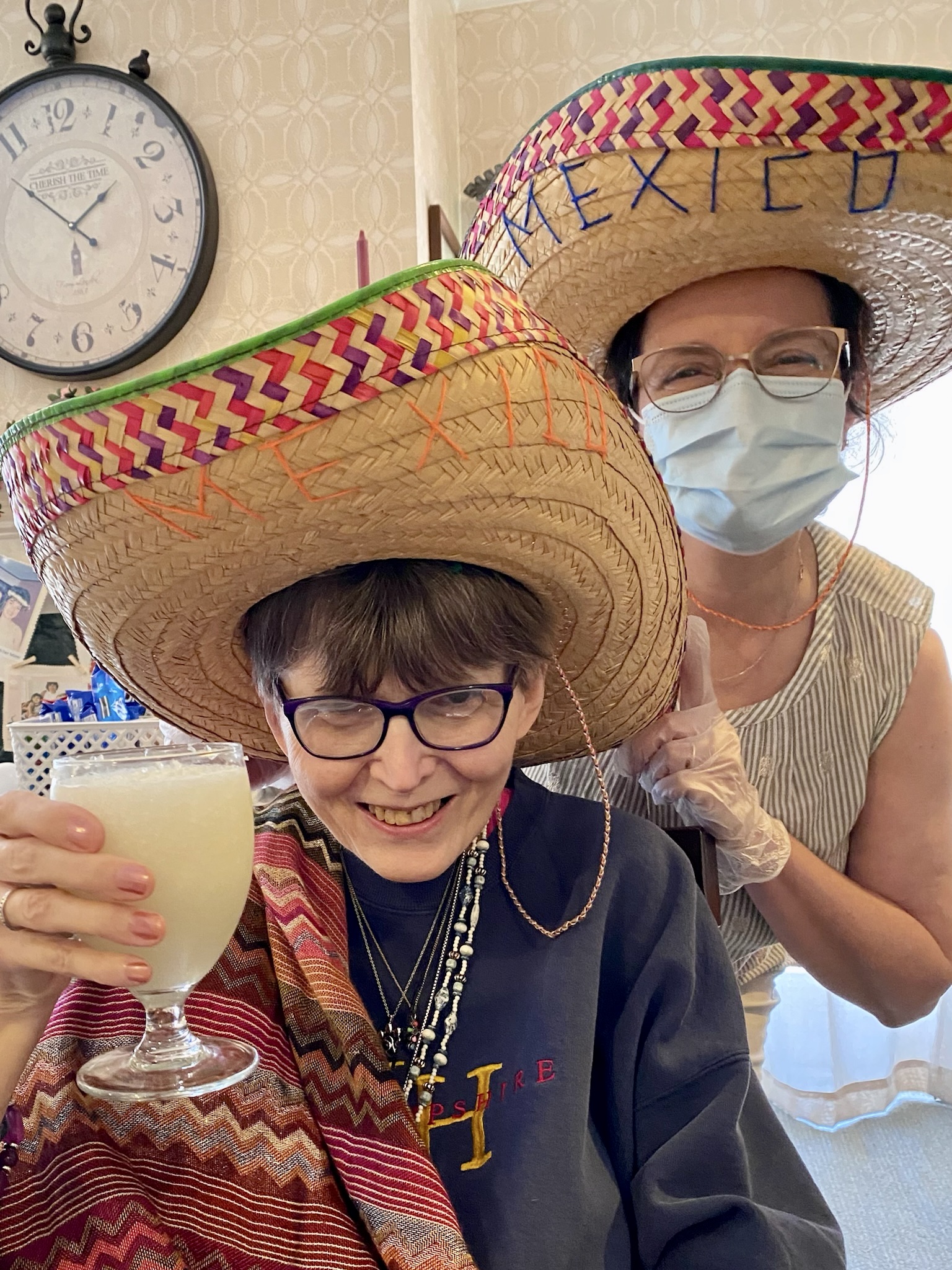 Residents celebrating with drinks and hats in an activity room