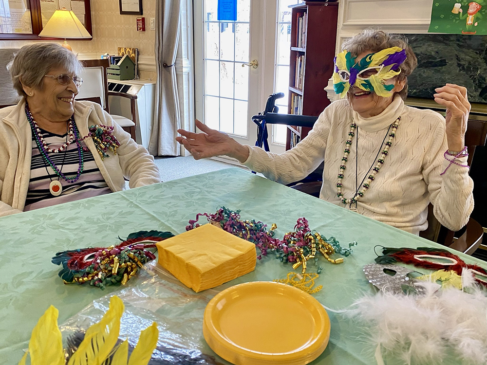 Two residents celebrating with masks and beads