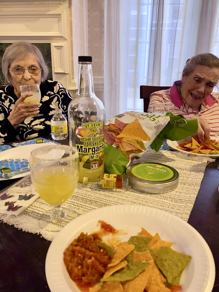Two senior women enjoying snacks and drinks at a table