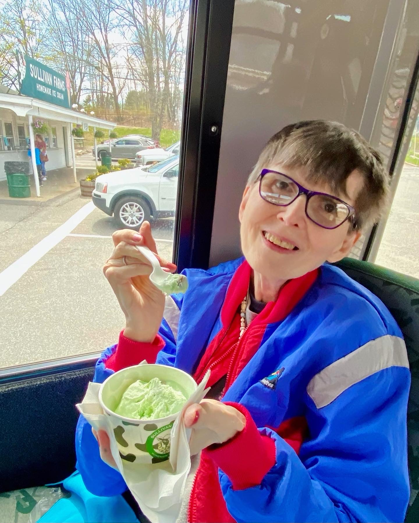 A smiling resident enjoying green ice cream on a bus