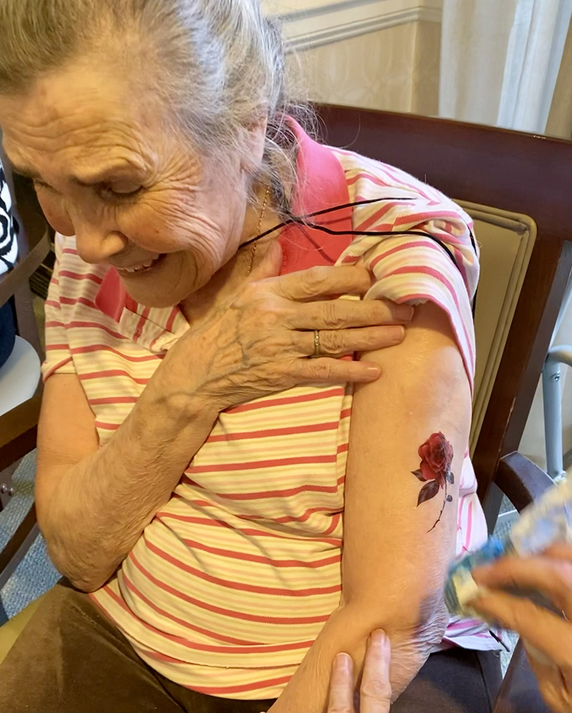 Elderly woman smiling while receiving a temporary tattoo