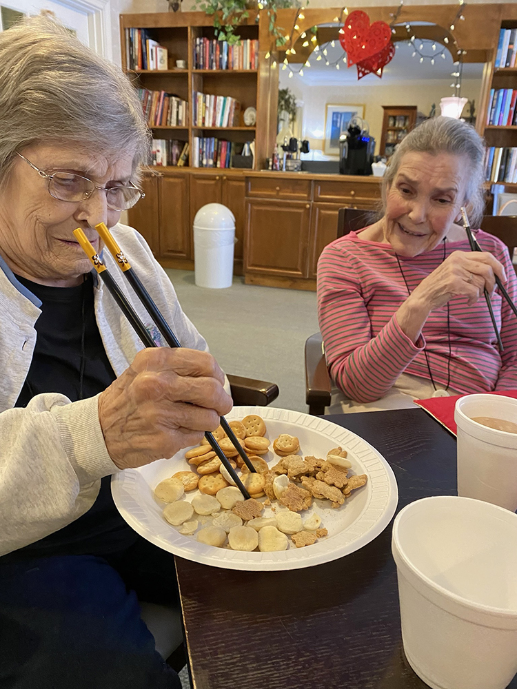 Two residents enjoying a meal using chopsticks