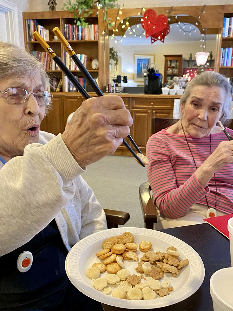 Residents enjoying snacks and using chopsticks in a common area