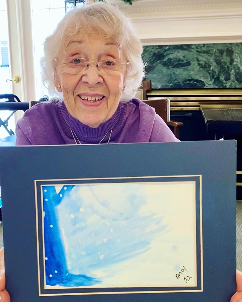 Elderly resident holding her watercolor painting