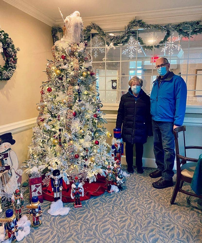 Residents posing with a decorated Christmas tree in the lobby