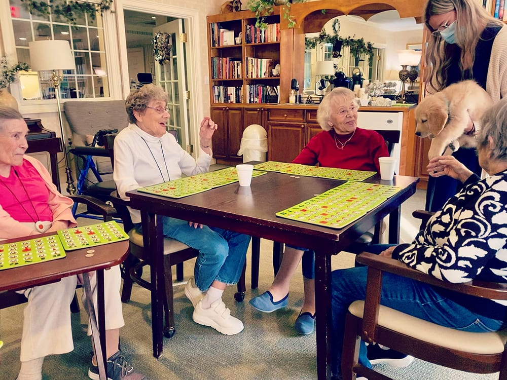 Residents enjoying a game with a puppy in a common area