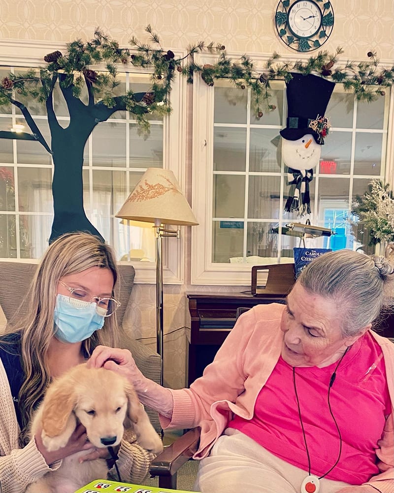 A resident interacting with a staff member and a puppy
