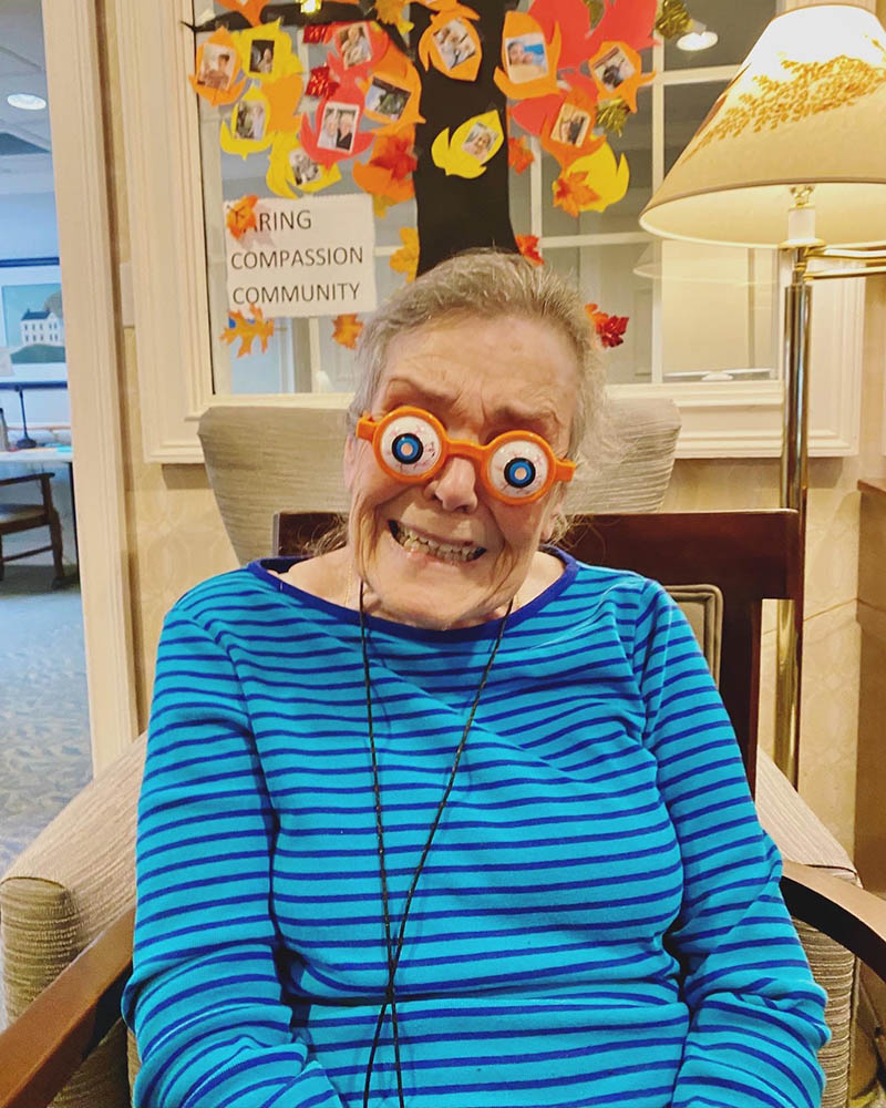 Resident with playful glasses in a cozy lounge