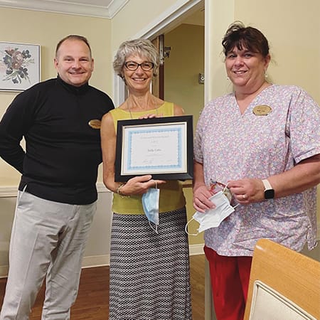 Staff and resident celebrating an achievement with an award